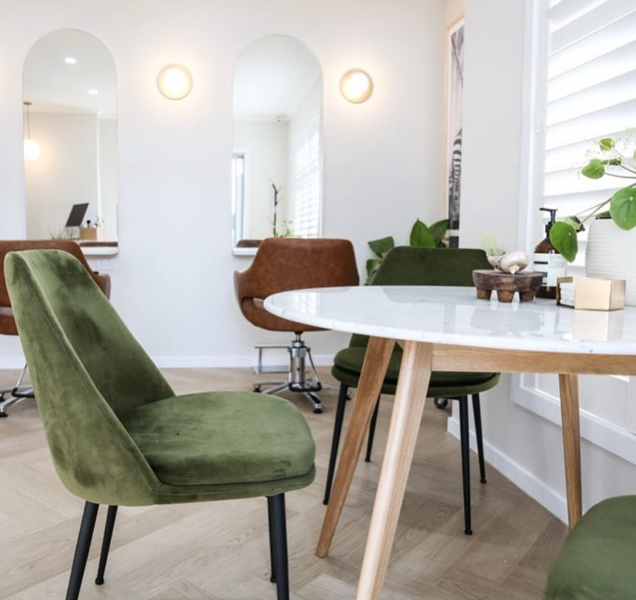 Arlo & Co salon interior with olive velvet chairs and arched mirrors